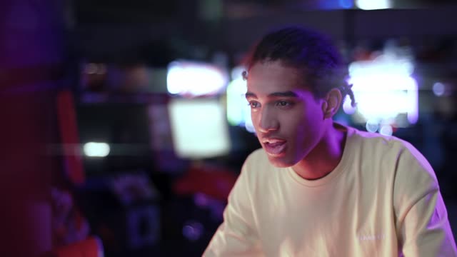 A vibrant arcade scene with a young man immersed in gaming fun.