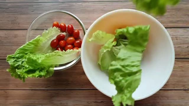 Preparing a fresh salad with lettuce, tomatoes, and onions in a kitchen setting.
