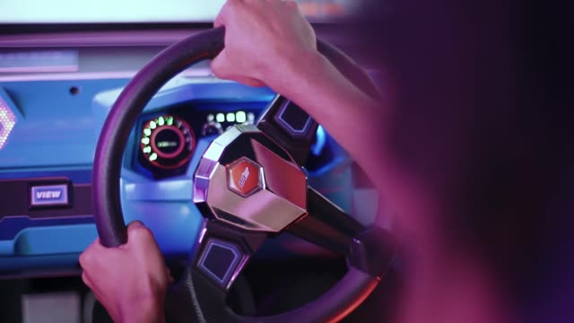 Neon-lit hands steer in a nostalgic arcade racing game session.