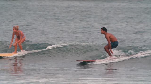 Two surfers catching waves, showcasing skill and balance on surfboards.