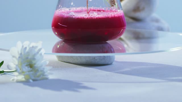 Close-up of a red liquid foaming in a glass flask during a chemistry experiment.