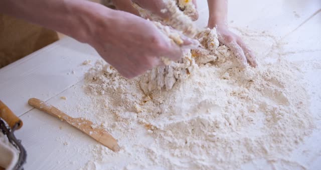Parent and child bond while baking together, kneading dough on a kitchen table.