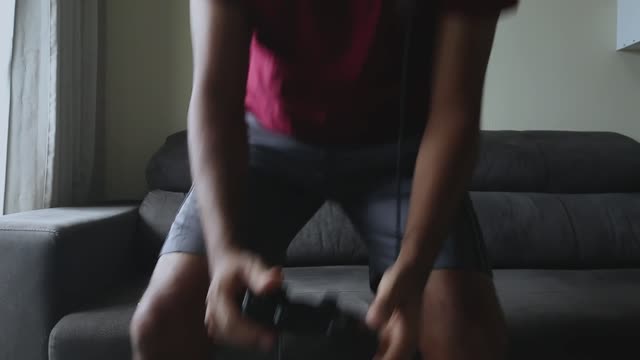 Focused gamer playing on console indoors, wearing headset.