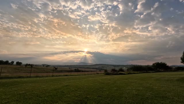 Capture of a stunning sunset over serene rural landscape with clouds.