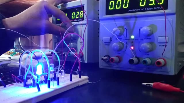 Close-up of hands testing electronic circuits with multimeter and blue LEDs.