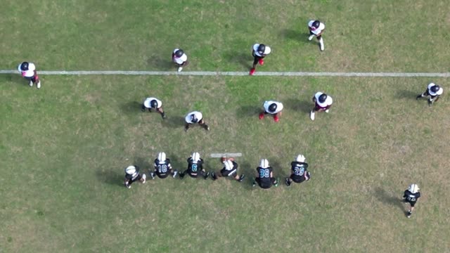 Drone footage capturing a football practice session from above.