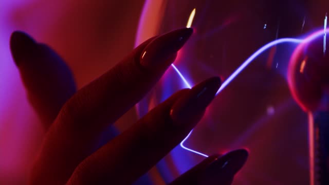 A close-up of a hand interacting with a glowing plasma ball, futuristic and scientific.