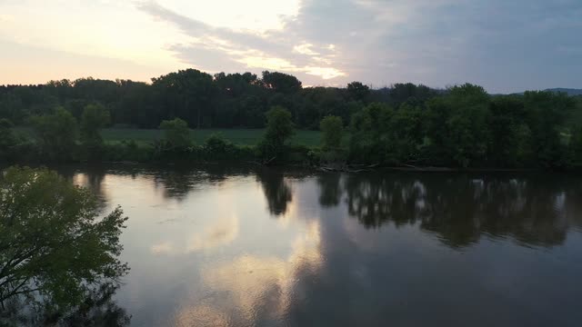 Peaceful river scene with sunset reflections, trees, and serene landscape.