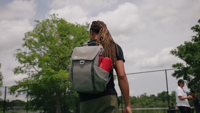 An adult with a backpack enjoys a sunny outdoor setting.