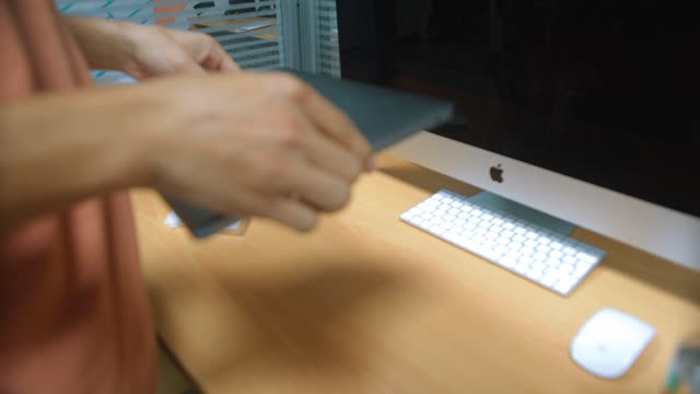A person cleaning and sanitizing a laptop in a modern home office setting.