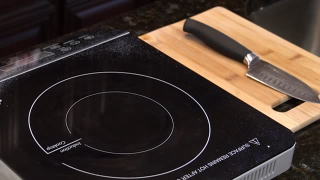 A modern induction cooktop with a frying pan and knife in the kitchen.