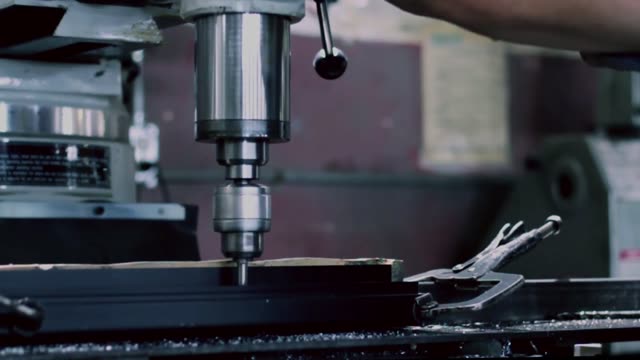 Close-up of metal grinding and drilling in a factory environment.