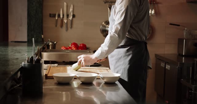 A chef slicing vegetables in a well-equipped kitchen with precision.