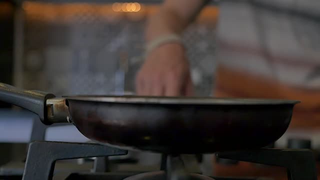 Close-up of a fried egg cooking on a gas stove with flame.