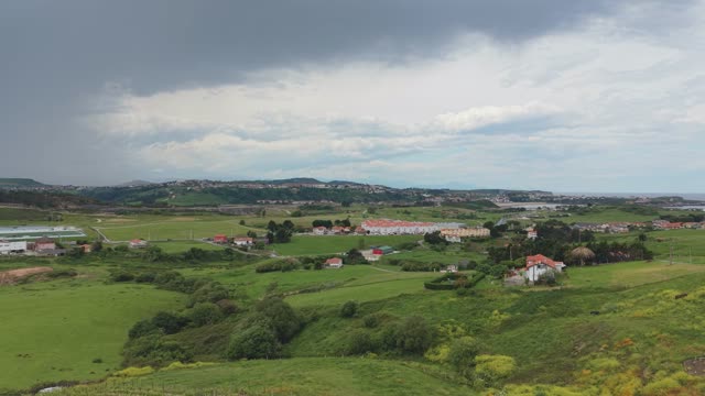 An aerial view showcasing the expansive green countryside with farms and rolling hills under a cloudy sky.