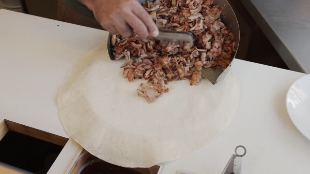 Close-up of hands making a tasty Turkish wrap with fresh ingredients.