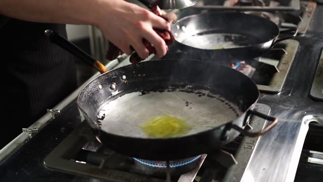 Chef prepares sizzling octopus in a frying pan, showcasing culinary artistry.