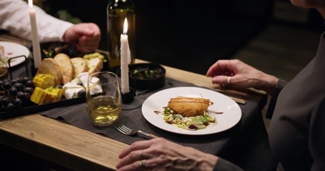 Elegant dinner with a senior couple enjoying wine and cheese by candlelight.