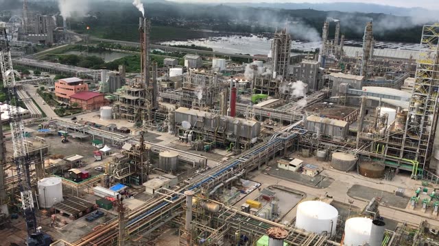 Aerial drone footage of a sprawling industrial plant next to a tranquil lake.