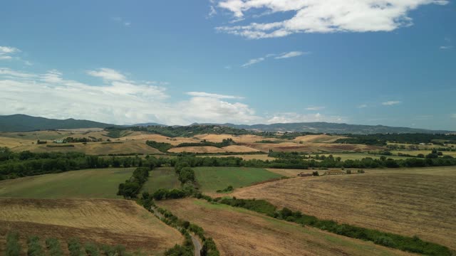Aerial drone footage showcasing the rolling hills of Tuscany in summer, with lush fields and blue skies.