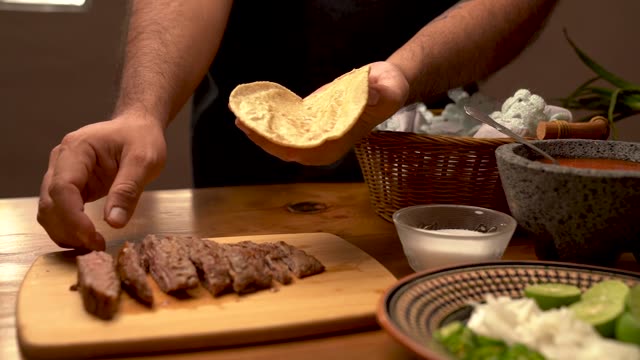 Close-up of preparing tacos with fresh ingredients and steak. Perfect for food enthusiasts.