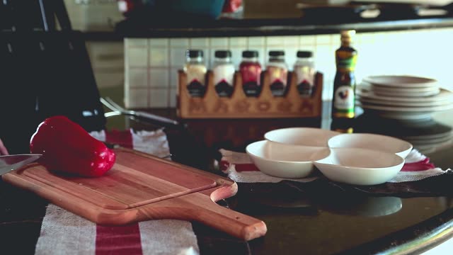 A close-up of vibrant red and yellow peppers being artfully sliced on a wooden board.