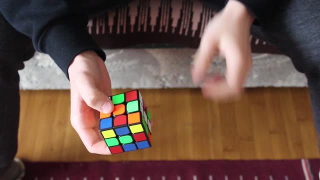 Hands skillfully manipulate a Rubik's cube in a close-up indoor setting.