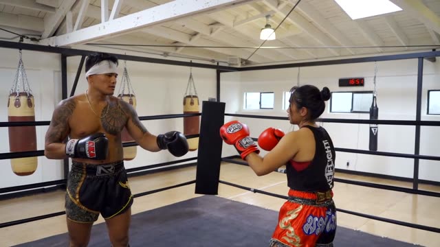 Intense Muay Thai training session featuring sparring and technique in a boxing gym.