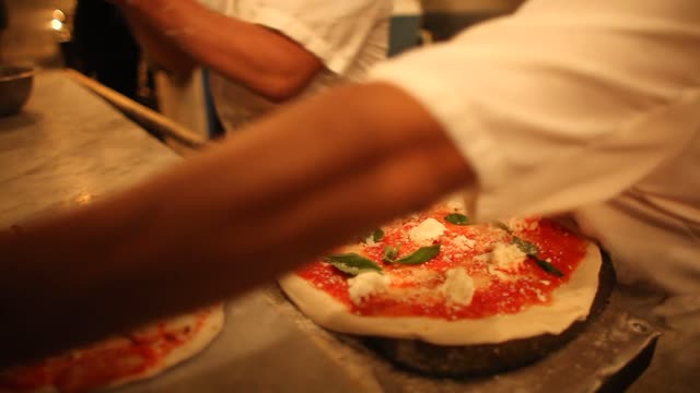 Chefs crafting artisan pizzas in a traditional pizzeria setting.
