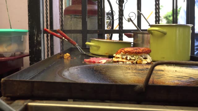 A delicious street food cooking scene with a sandwich being grilled.