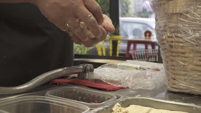 Hands preparing Mexican street food dough in a busy kitchen setting.