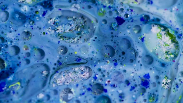 Dynamic close-up of colorful ink and liquid bubbles in slow motion, showcasing a vibrant abstract pattern.