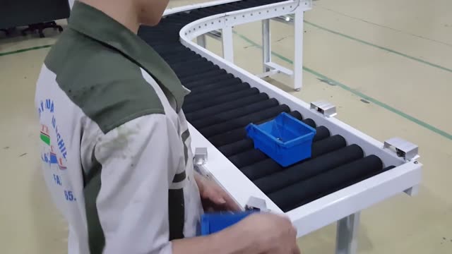 Worker managing assembly on a conveyor belt in a factory setting.