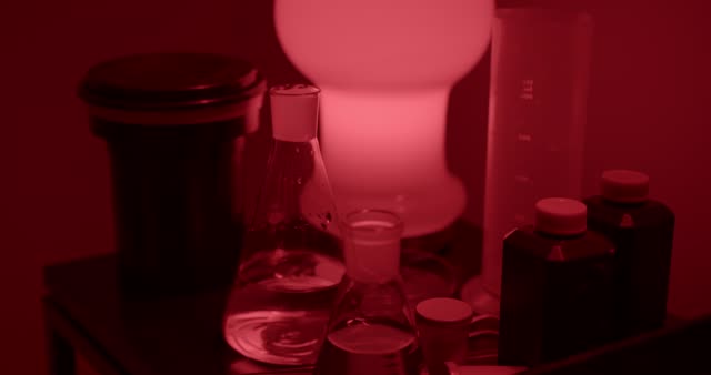 Close-up of developing film in a darkroom with red lighting.