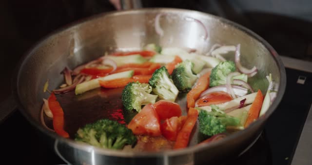 Colorful vegetables sizzling in a hot pan with steam rising.
