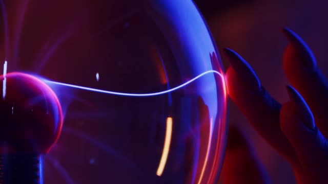 Close-up of a hand interacting with a glowing plasma ball, showcasing electrical energy.