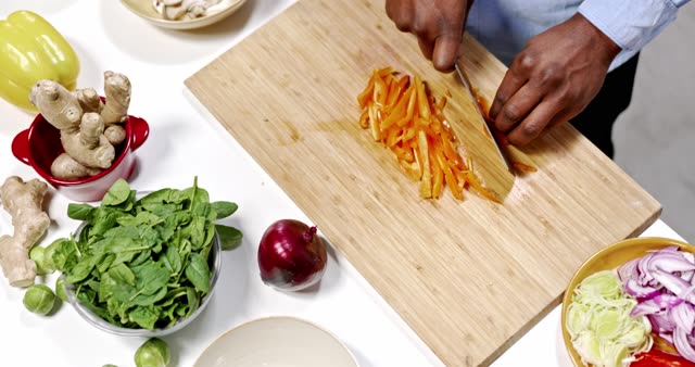 Chef slicing colorful veggies on a wooden board for a healthy meal.