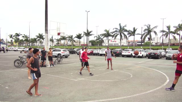 Energetic outdoor basketball game with diverse players in an urban setting.