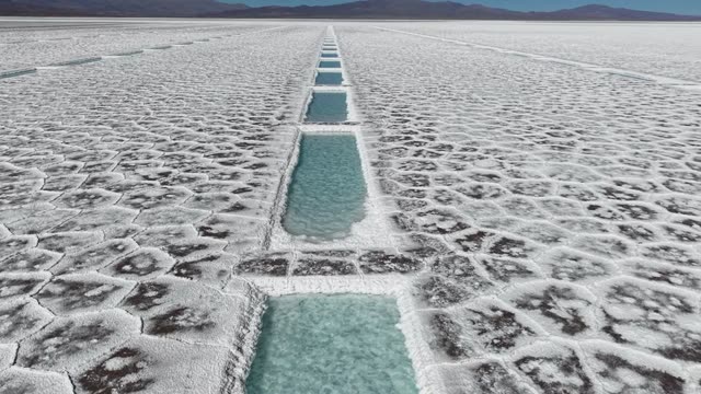 Stunning aerial view of salt flats featuring geometric white salt and blue mineral pools.
